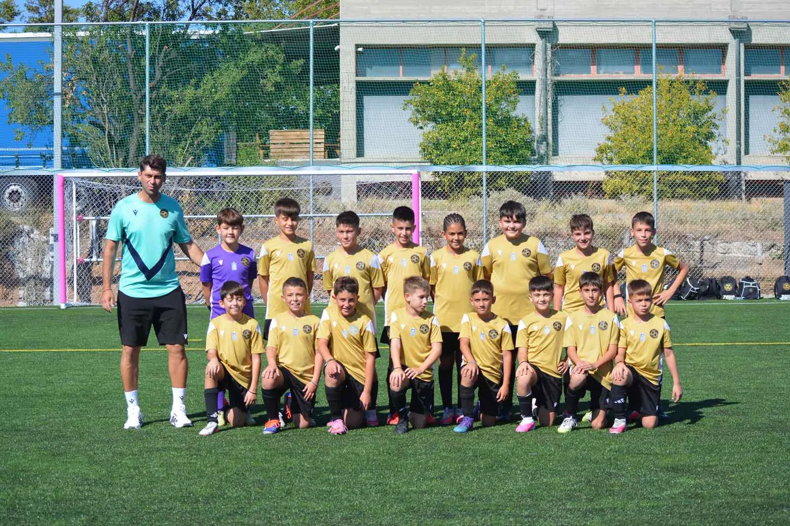Ομαδική φωτογραφία του τμήματος Κ11 της ALANA FC Academy με τον προπονητή του πριν από ποδοσφαιρικό αγώνα.